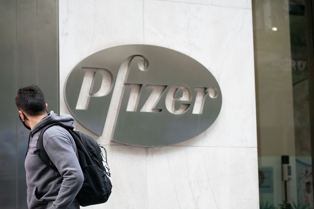 A man wearing a face mask walks past a Pfizer logo at their headquarters on September 14th, 2020.
